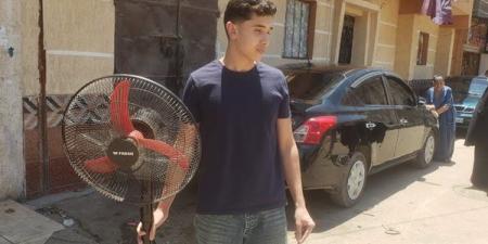 شاب يحضر مروحة لشقيقته أمام لجنة الثانوية العامة بالبحيرة لمواجهة حرارة الطقس